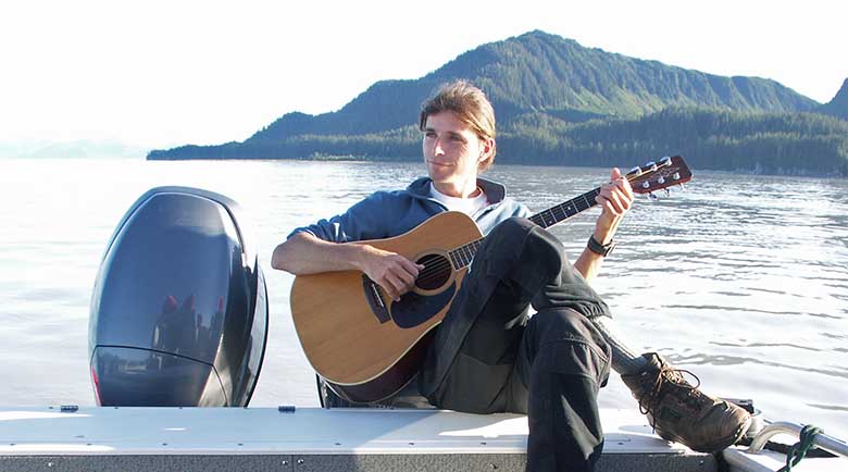 Justin Smith playing guitar on a boat in Cross Sound, Southeast Alaska